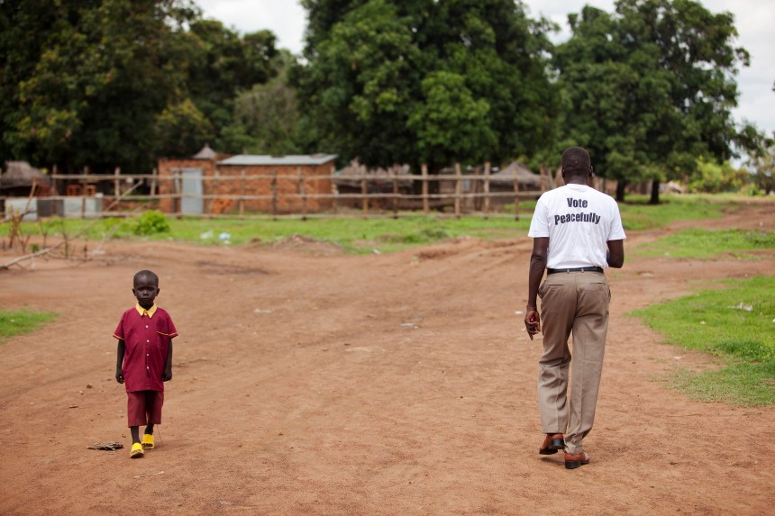 A man wearing a t-shirt to promote voting in the referendum passes a child on the way to school in Mundri, South Sudan, a week before the country gained independence.